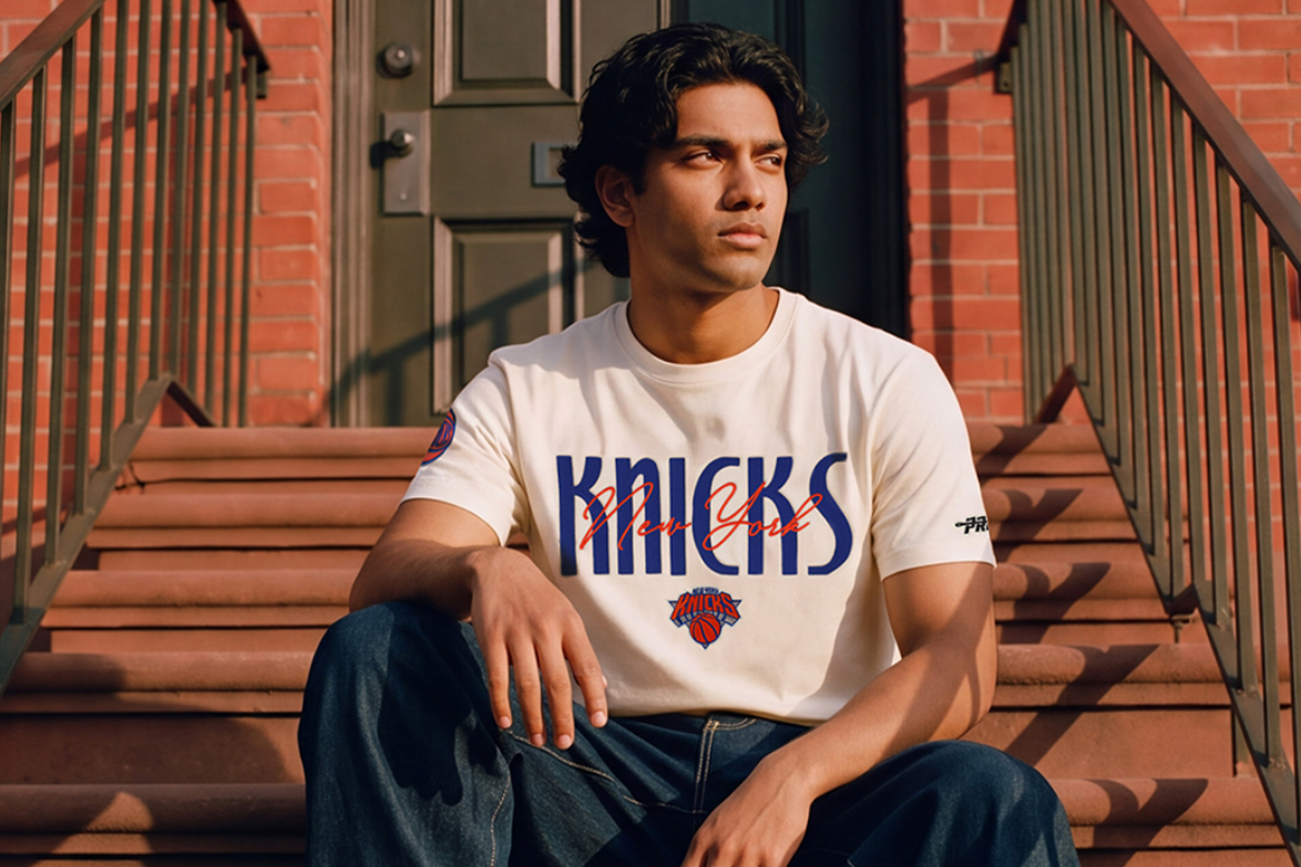 Man wearing Pro Standard Knicks apparel seated on urban steps