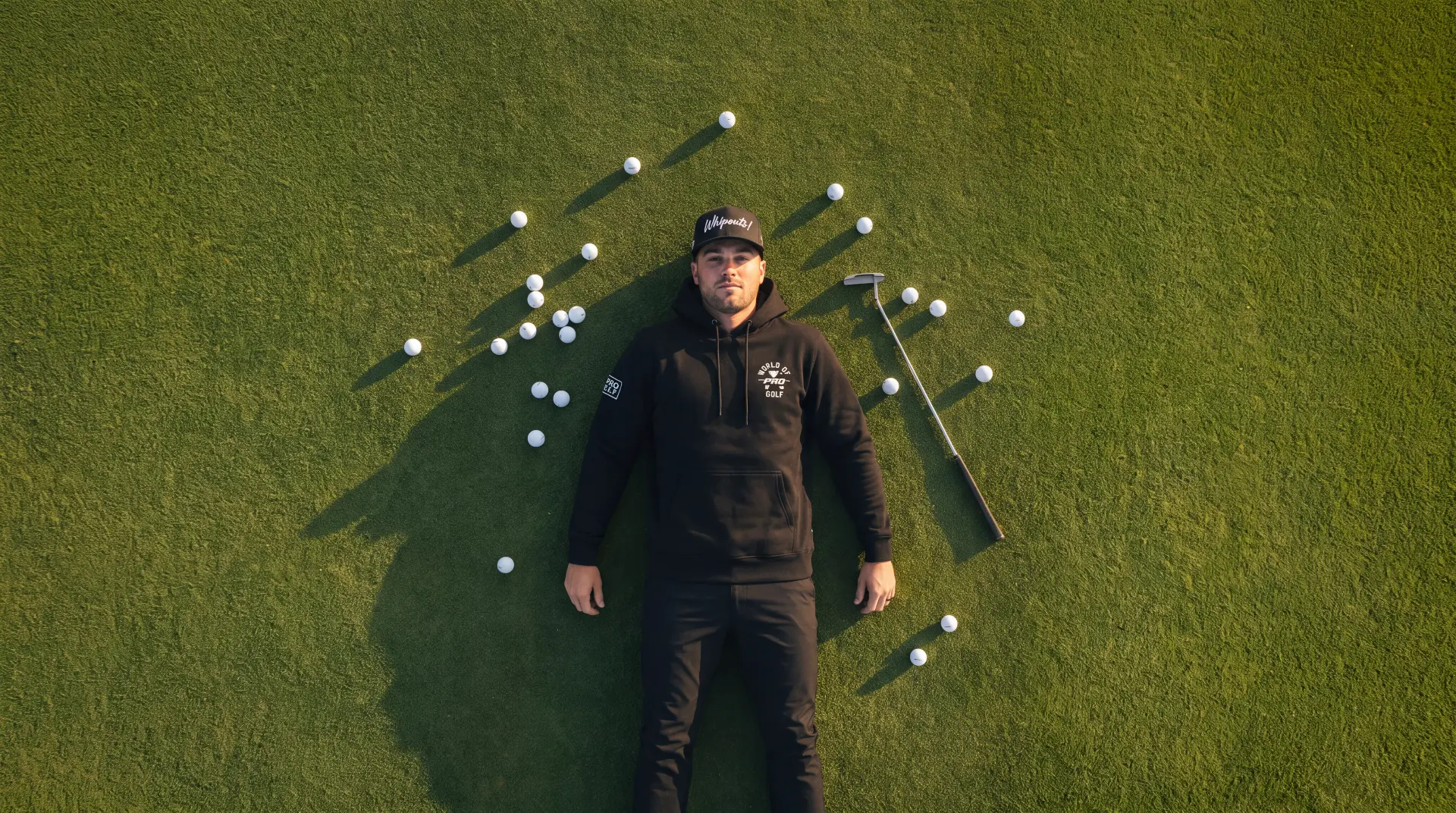 Model in the white signature hoodie lying on the putting green
